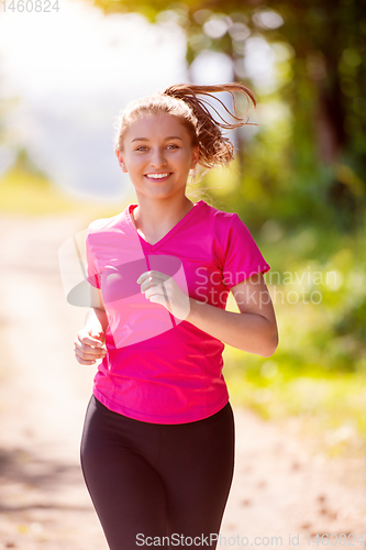 Image of young woman jogging on sunny day at nature