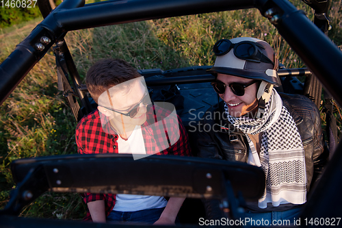 Image of two young men driving a off road buggy car