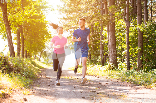 Image of young couple jogging on sunny day at nature