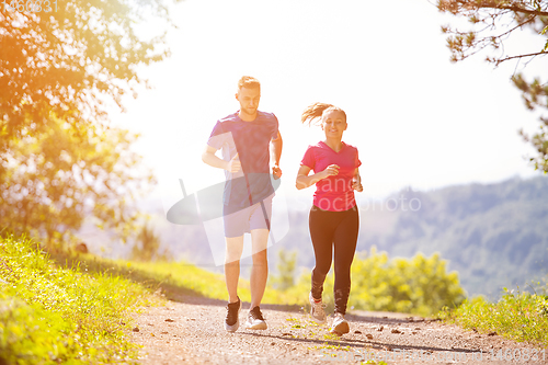 Image of young couple jogging on sunny day at nature