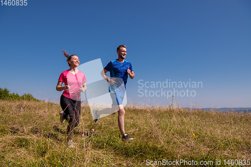 Image of young couple jogging on sunny day at summer mountain