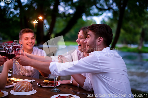 Image of happy friends having french dinner party outdoor