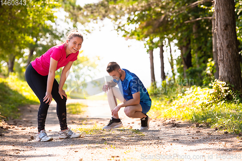 Image of young couple warming up and stretching on sunny day at nature