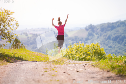 Image of young woman jogging on sunny day at nature
