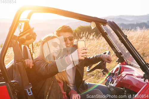 Image of young couple taking selfie picture while driving a off road bugg