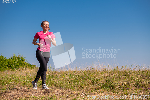 Image of young woman jogging on sunny day at summer mountain