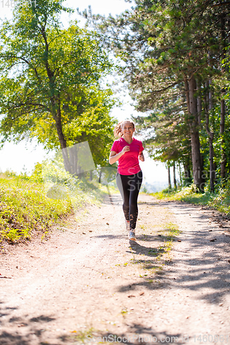 Image of young woman jogging on sunny day at nature