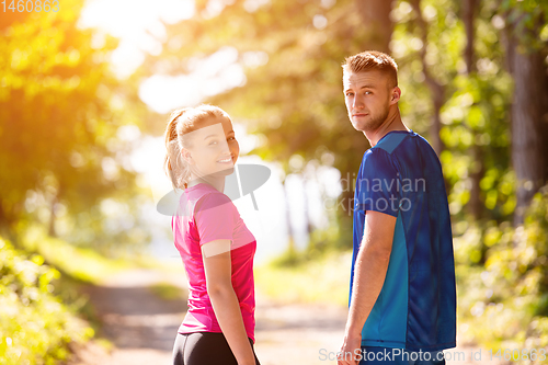 Image of portrait of young couple jogging on sunny day at nature