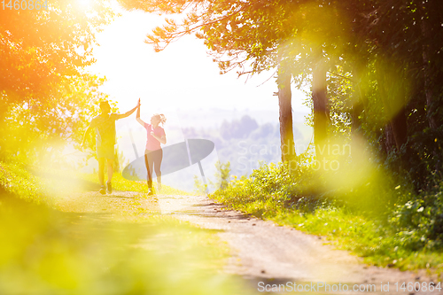 Image of jogging couple giving high five to each other on sunny day at na