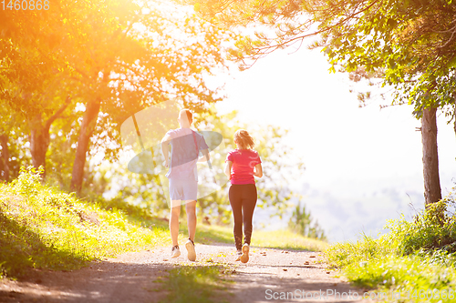 Image of young couple jogging on sunny day at nature