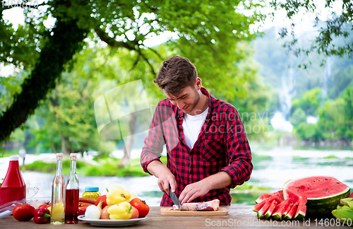 Image of Man cutting meat for barbecue grill