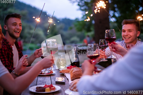 Image of happy friends having french dinner party outdoor