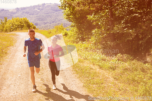 Image of young couple jogging on sunny day at nature