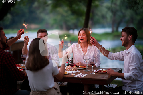 Image of happy friends having french dinner party outdoor