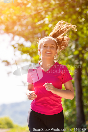 Image of young woman jogging on sunny day at nature