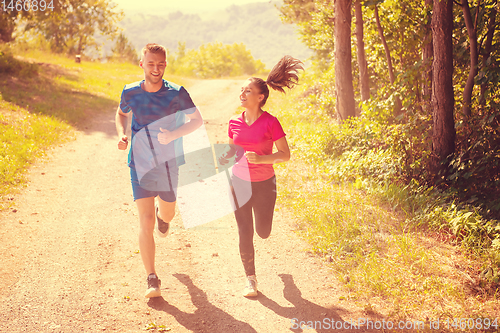 Image of young couple jogging on sunny day at nature