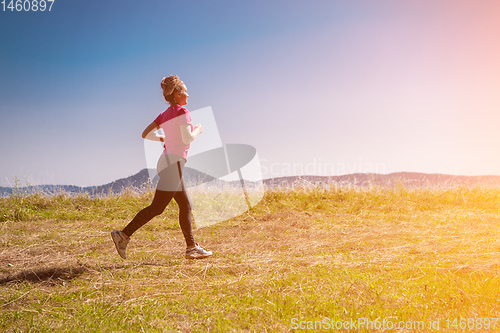 Image of young woman jogging on sunny day at summer mountain