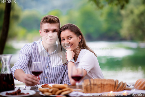 Image of happy couple having picnic french dinner party outdoor