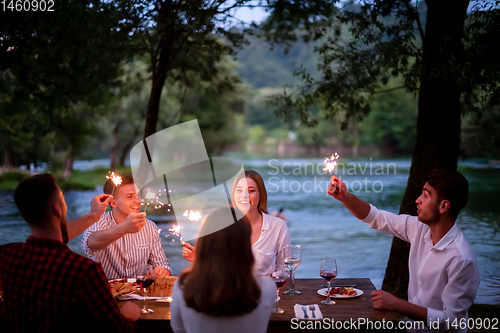 Image of happy friends having french dinner party outdoor