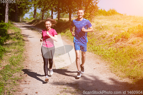 Image of young couple jogging on sunny day at nature
