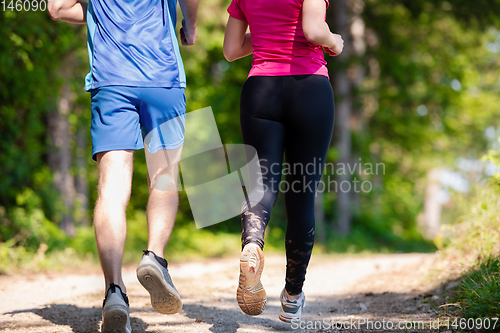 Image of young couple jogging on sunny day at nature