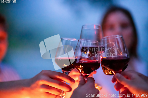 Image of friends toasting red wine glass during french dinner party outdo