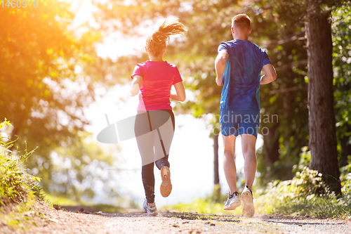 Image of young couple jogging on sunny day at nature