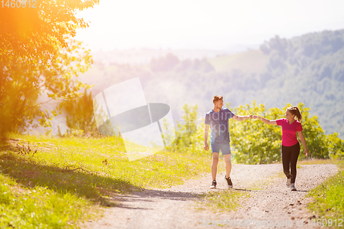 Image of young couple jogging on sunny day at nature
