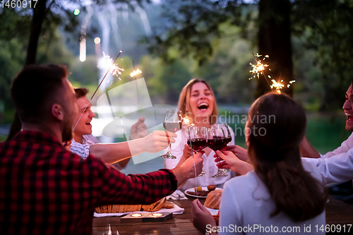 Image of happy friends having french dinner party outdoor