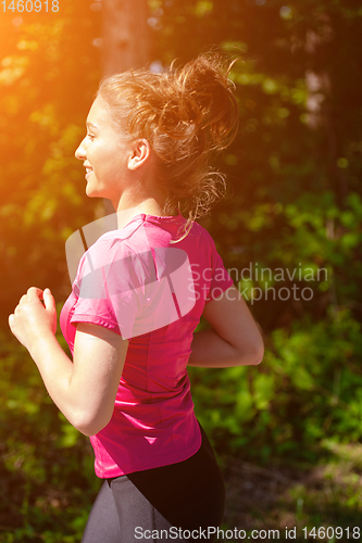 Image of young woman jogging on sunny day at nature