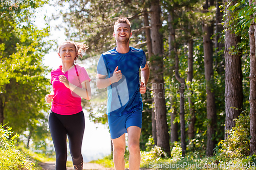 Image of young couple jogging on sunny day at nature