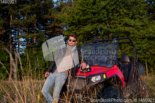 Image of young man taking a break from driving a off road buggy car