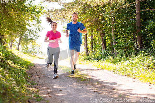Image of young couple jogging on sunny day at nature