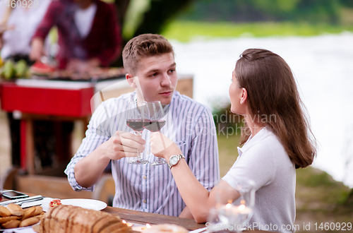 Image of happy couple toasting red wine glass during french dinner party 