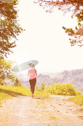 Image of young woman jogging on sunny day at nature