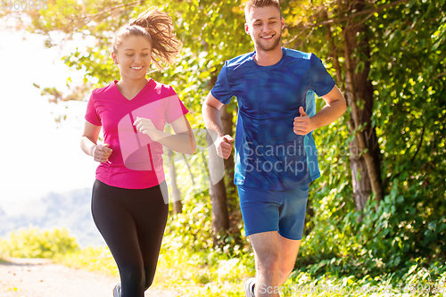 Image of young couple jogging on sunny day at nature