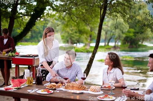 Image of happy friends having picnic french dinner party outdoor