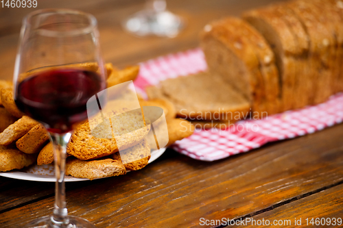 Image of glass of red wine and toasted bread on wooden table