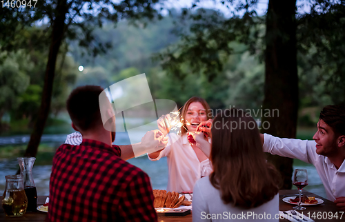 Image of happy friends having french dinner party outdoor