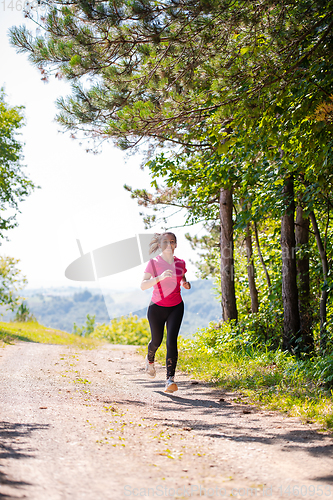 Image of young woman jogging on sunny day at nature