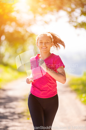 Image of young woman jogging on sunny day at nature