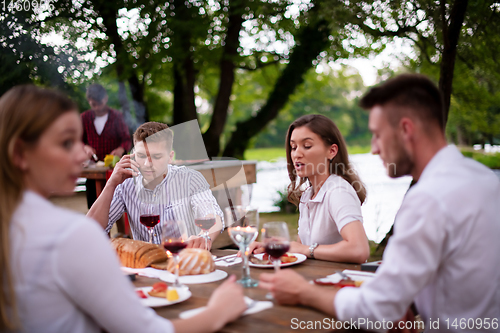 Image of happy friends having picnic french dinner party outdoor