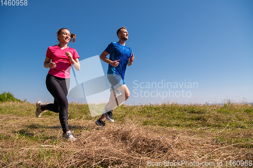 Image of young couple jogging on sunny day at summer mountain
