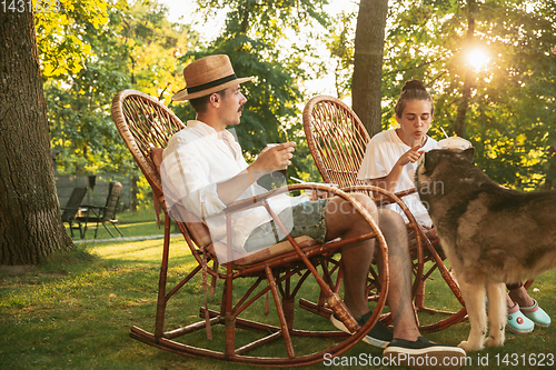 Image of Happy couple eating and drinking beers at barbecue dinner on sunset time