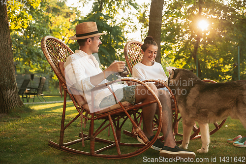 Image of Happy couple eating and drinking beers at barbecue dinner on sunset time