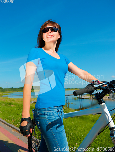 Image of Young woman is standing in front of her bicycle