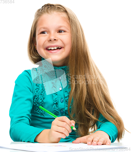 Image of Little girl is drawing using pencils