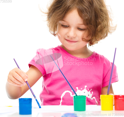 Image of Little girl is painting with gouache