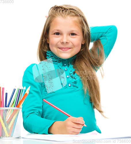 Image of Little girl is drawing using pencils