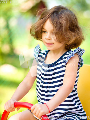 Image of Young happy girl is swinging in playground